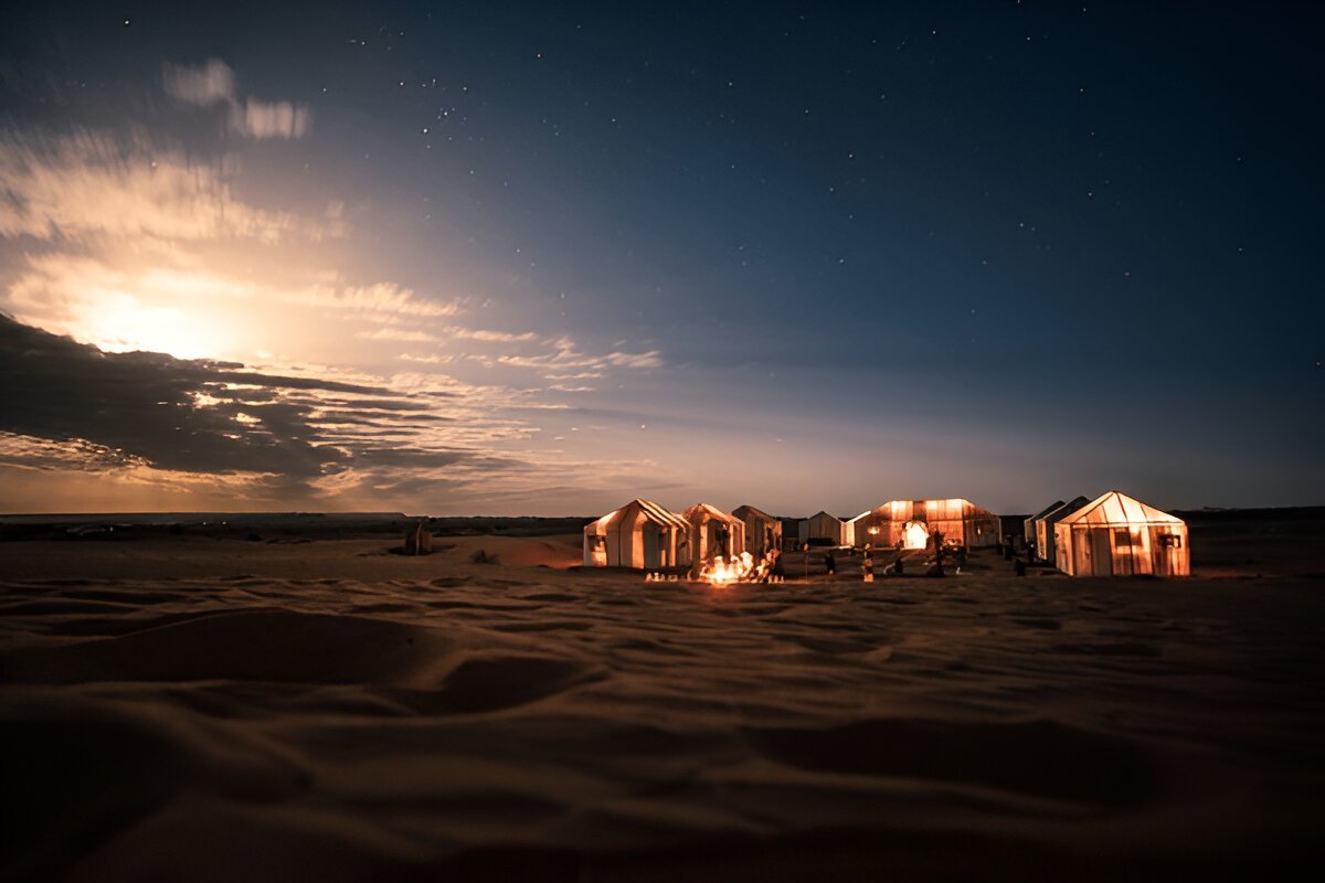 Large Arabian-style tent with plush seating and a fire show performance in the desert under a starlit sky. @exploredesertsafari.com